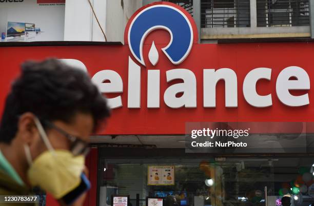 Man on phone walks past a Reliance logo in Kolkata, India, 25 January, 2021. Reliance Industries' profit jumped in the final quarter of 2020 as it...