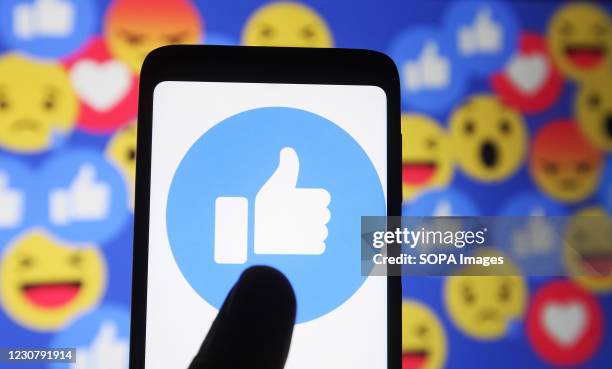 In this photo illustration a thumb up sign emoji and smiley face icons of Facebook are seen displayed on a mobile phone and a pc screen.