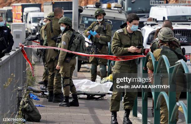 Israeli soldiers gather by the body of a Palestinian man who was shot dead reportedly while attempting a knife attack at the Gitai Avisar Junction,...