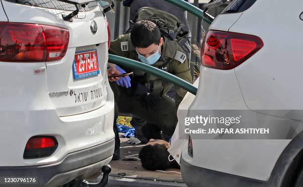 An Israeli soldier checks the body of a Palestinian man who was shot dead reportedly while attempting a knife attack at the Gitai Avisar Junction,...