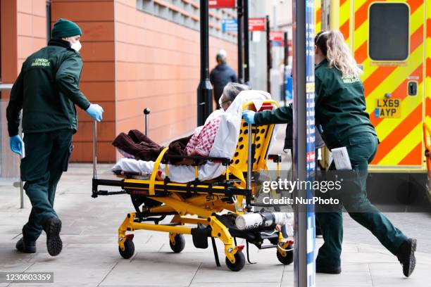 Paramedics wheel a patient wearing an oxygen mask into the emergency department of the Royal London Hospital in London, England, on January 26, 2021....
