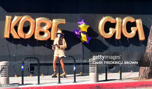 Woman skates past a memorial for former Los Angeles Laker Kobe Bryant and his dauhgter Gianna along a wall in downtown Los Angeles, California on...