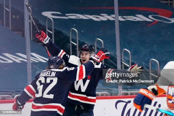 Justin Schultz of the Washington Capitals celebrates with teammate Carl Hagelin after scoring the game-winning goal against the New York Islanders in...