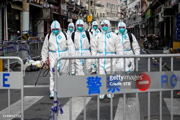 Health workers in protective gear walk out from a blocked off area after spraying disinfectant in Shanghai's Huangpu district on January 27 after...