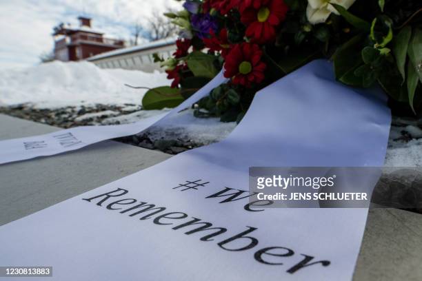 Flowers and a wreath with the inscription "# We Remember" are placed on a commemorative plaque at the memorial site of the former Nazi concentration...