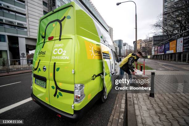 Worker unloads parcels from an InPost SA electric van, manufactured by Nissan Motor Co., in Warsaw, Poland, on Wednesday, Jan. 27, 2021....