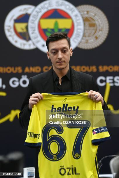 German midfielder Mesut Ozil poses with his jersey after signing his new three-and-a-half year contract with Turkish football club Fenerbahce at the...