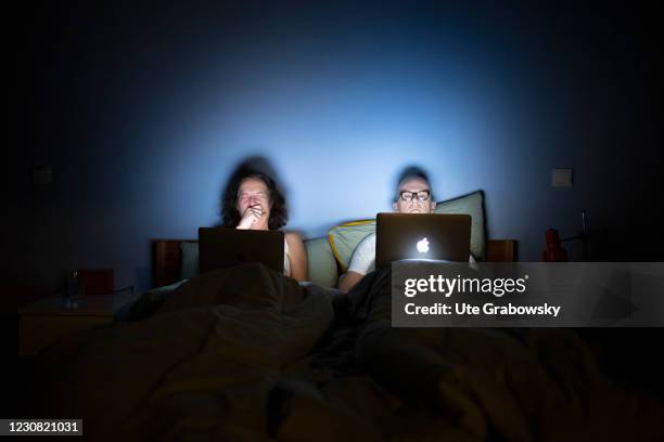 In this photo illustration a man and a woman are lying in bed, looking at a laptop computer on January 26, 2021 in Bonn, Germany.