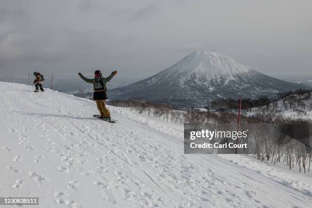 Snowboarder gestures with Mount Yotei in the background on January 28, 2021 in Niseko, Japan. As one of Asias most popular ski resorts, Niseko...