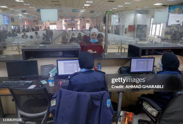 Palestinian police officers check the papers of a few travelers at the departure hall of the border crossing with Jordan, in the city of Jericho in...