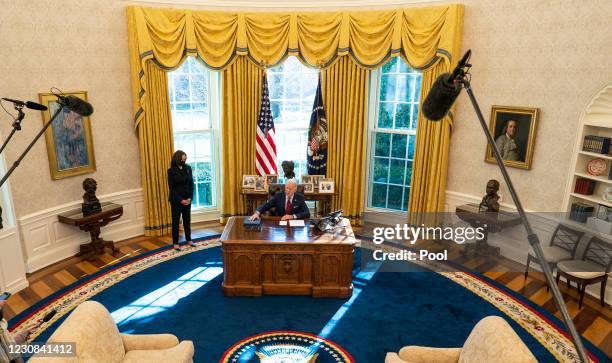 Vice President Kamala Harris looks on as U.S. President Joe Biden speaks to reporters before signing executive actions in the Oval Office of the...