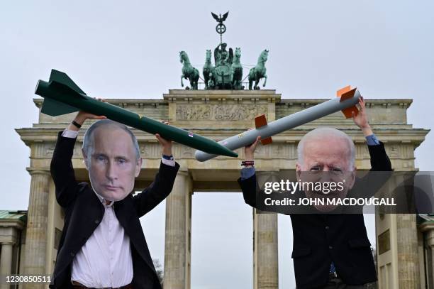 Peace activists wearing masks of Russian President Vladimir Putin and newly elected US President Joe Biden pose with mock nuclear missiles in front...