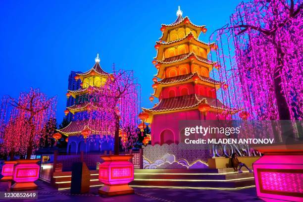 Woman rests under a festive installation of illuminated pagodas erected outside a shopping mall to celebrate the upcoming Lunar New Year in Bangkok...
