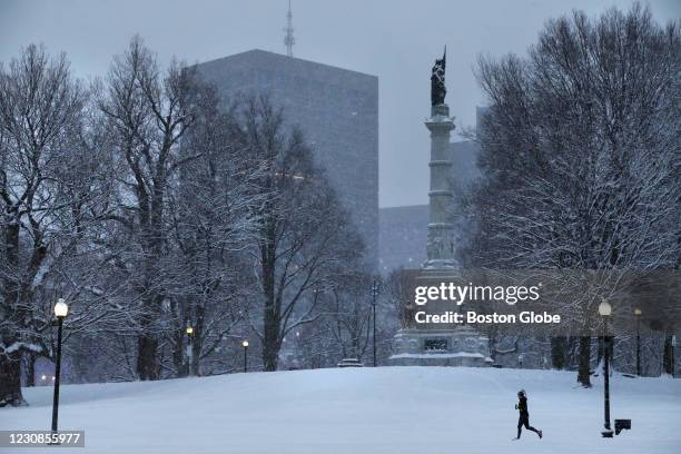 Woman jogs through a snow covered Boston Common in Boston, MA on January 27, 2021. Scattered snow showers and a wintery mix continued into Wednesday...