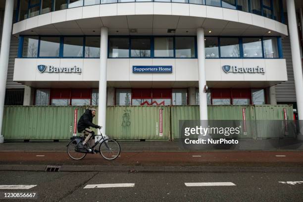 Man is passing infront of the shipping containers outside of the stadium, cycling on bicycles. The Philips Stadion, PSV club stadium in the Dutch...