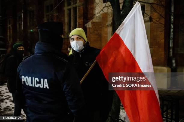 Protester wearing a face mask holds a Polish national flag while talking to a policeman during the demonstration. After the Polish Constitutional...