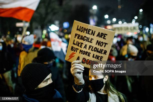 Protester wearing a face mask holds a placard saying Woman are fragile, not like a flower but more like a bomb during the demonstration. After the...