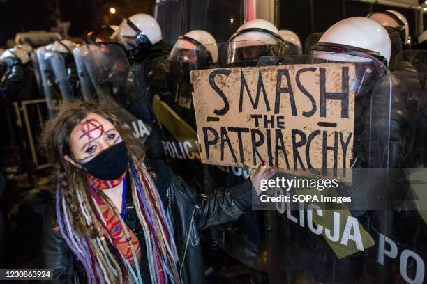 Protester holds a placard in front of a riot policeman during the demonstration. Thousands of people protested for a third consecutive night in...