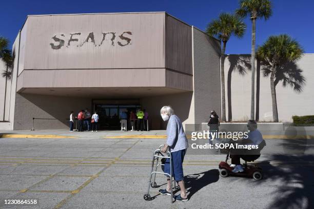 People are seen outside a walk-in COVID-19 vaccination POD inside a vacant Sears store at the Lake Square Mall. The appointment-only site for...
