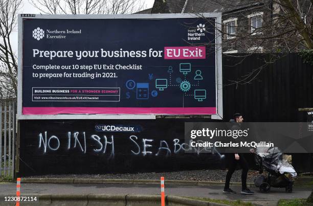Man walks past freshly painted graffiti in the loyalist Sandy row area which states No Irish sea border under an EU Exit billboard on January 30,...