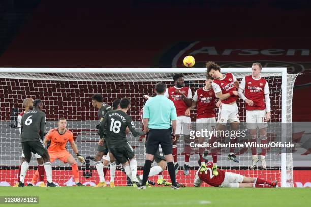 Bruno Fernandes of Manchester United strikes a free-kick over the defensive wall as David Luiz of Arsenal gets a head to it during the Premier League...