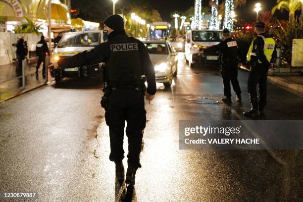 French police officers gesture as they control "exit permit" of drivers on the road by the "Promenade des anglais", during the curfew hours, on the...