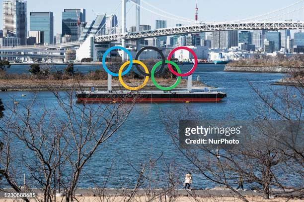 People walk their dogs along the coast where displayed the Olympic Symbol at the Odaiba marine park in Tokyo, Japan on 30 January, 2021.