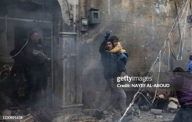 Civilians carry young victims at the scene of an explosion in the town of Azaz in the rebel-controlled northern countryside of Syria's Aleppo...