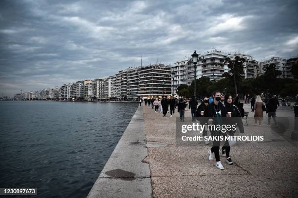 People walk in the waterfront of Thessaloniki, Greece, on January 31, 2021. - A first case of contamination with the Covid-19 variant that emerged in...