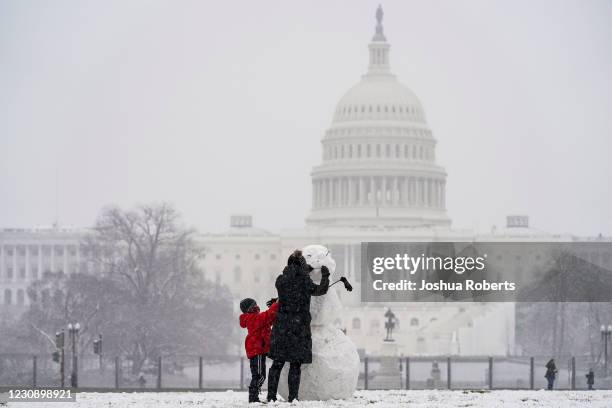 Janine Iselmann and her son Max build a snowman on the National Mall during a snow storm on January 31, 2021 in Washington, DC. Washington is...