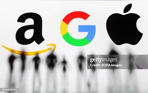 In this photo illustration Google, Amazon and Apple logos seen displayed behind silhouettes of model/toy people.