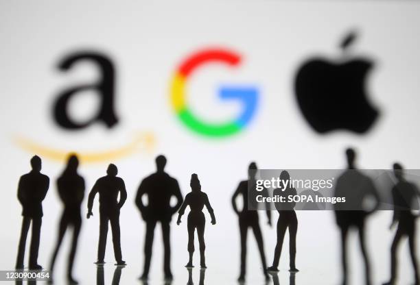 In this photo illustration Google, Amazon and Apple logos seen displayed behind silhouettes of model/toy people.