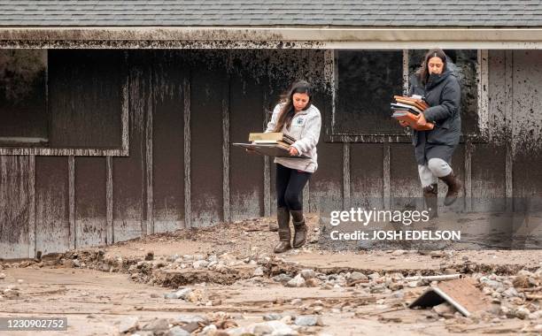 Residents remove items from a home damaged by a mud flow in Salinas, California on January 27 as heavy rain fell on a fire burned hillside sending...