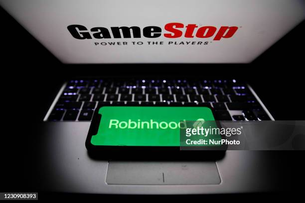 Robinhood logo displayed on a phone screen and GameStop logo displayed on a laptop screen are seen in this illustration photo taken in Poland on...