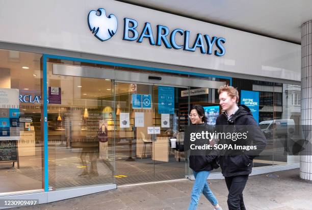 Pedestrians walk past Barclays bank, a British multinational investment bank and financial services company, in London.