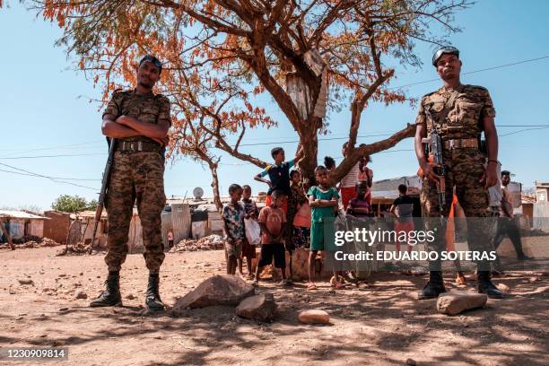 Ethiopian Army soldiers stand as a children stand behind them at Mai Aini Refugee camp, in Ethiopia, on January 30, 2021. - Eritrean refugees in...