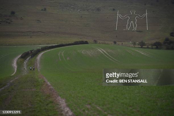 Walkers approach the Long Man of Wilmington carved into the hillside near Eastbourne on southern England on February 1, 2021. Vandals had painted a...