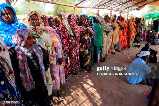 Displaced Sudanese women wait for the arrival of the World Food Programme aid in the Otash internally displaced people's camp on the outskirts of...