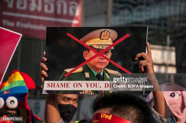 Supporter holds a crossed-out portrait of Myanmar's army chief Min Aung Hlaing during the demonstration. National League for Democracy supporters and...