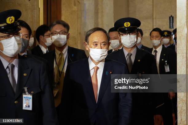 Japan's Prime Minister Yoshihide Suga walks with security guards inside the parliament building before a debate session regarding the bills to...