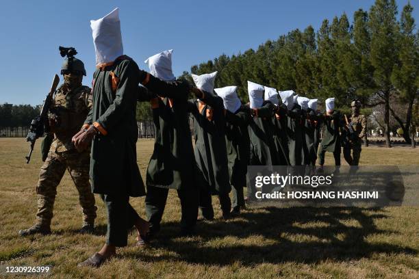 Afghan security forces escort suspected Taliban fighters as they are being presented in front of the media after an operation at the National...