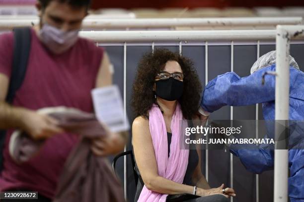 Health worker receives a dose of the Sputnik V vaccine against COVID-19, at the basketball court of Argentine club River Plate, bellow the grandstand...