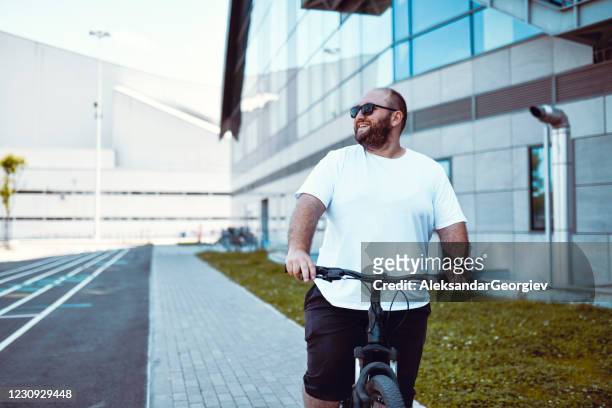 balding happy male usando la bicicleta para bajar de peso - hombre sobrepeso fotografías e imágenes de stock