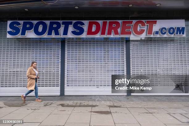 Woman walks past shuttered closed Sports Direct shop along Oxford Street which is largely empty of shoppers as the national coronavirus lockdown...