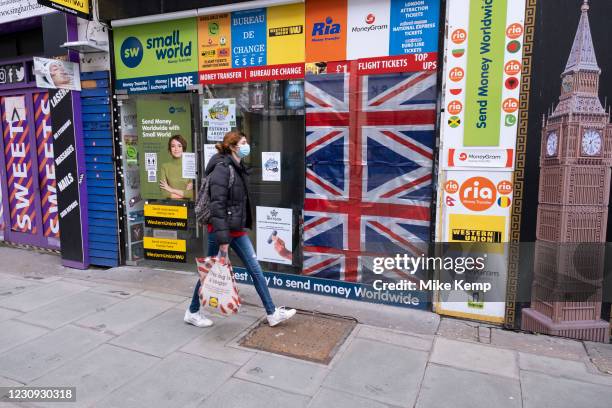 Woman wearing a face mask walks past shuttered closed money transfer shop along Oxford Street which is largely empty of shoppers as the national...