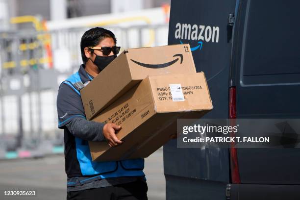 An Amazon.com Inc. Delivery driver carries boxes into a van outside of a distribution facility on February 2, 2021 in Hawthorne, California. - Jeff...
