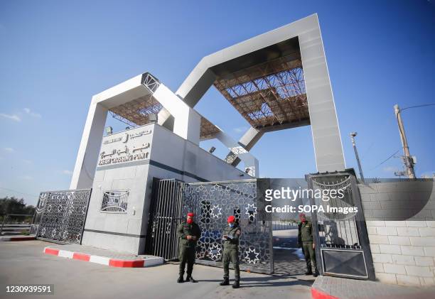 Palestinian security forces wearing face masks stand alert at the gate of the Rafah border crossing. Palestinians wait for their travel permits to...