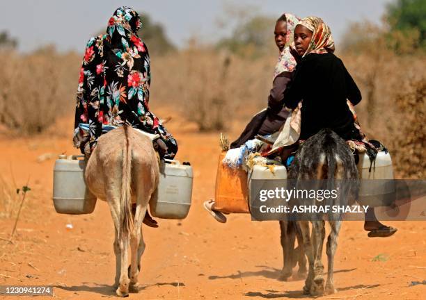 Sudanese women transport water on donkeyback in the village of al-Twail Saadoun, 85 kilometres south of Nyala town, the capital of South Darfur, on...