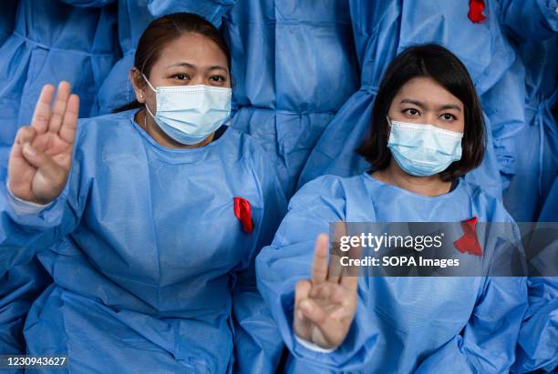 Medical staffs wearing facemasks and red ribbon tags raise the three finger salutes in protest against the military coup. Myanmar's military detained...