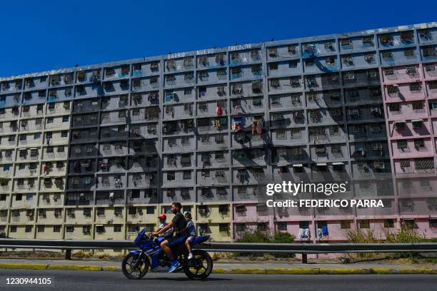 Man and children ride a motorbike by a building portraying the eyes of late Venezuelan president Hugo Chavez at 23 de Enero neighbourhood in Caracas...